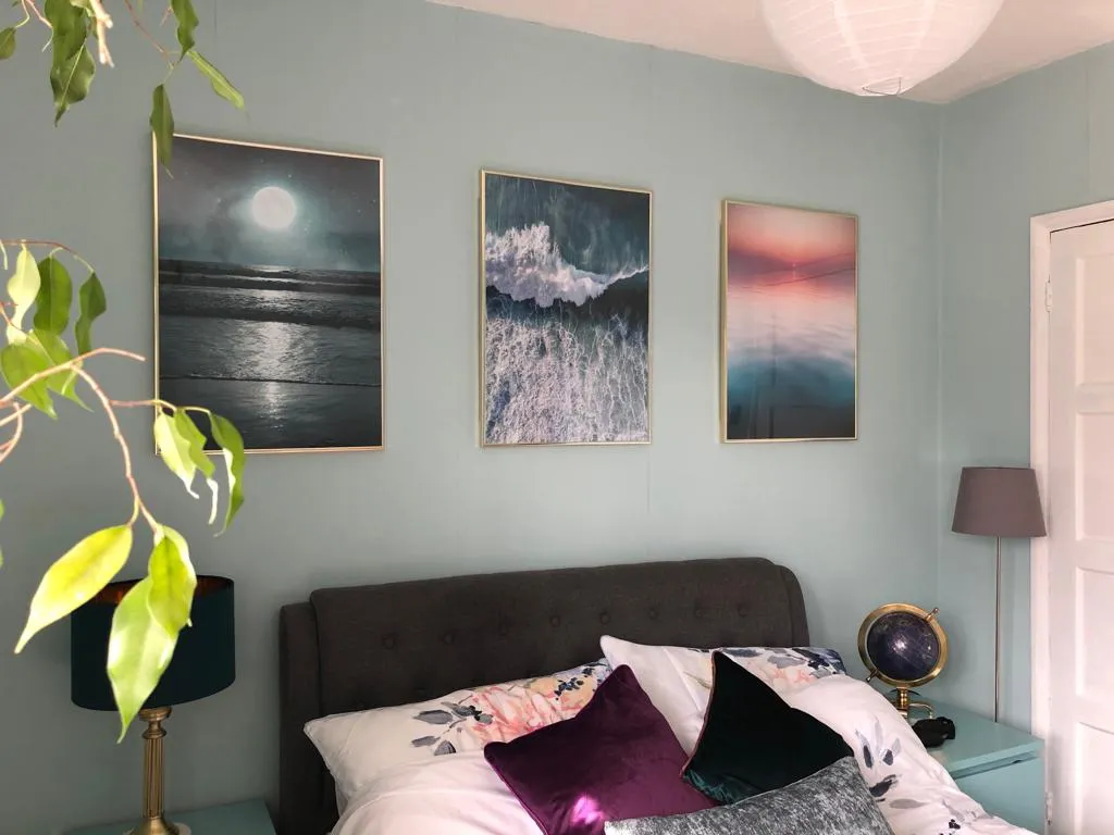 Desenio Prints and Frames above a double bed on a light blue wall