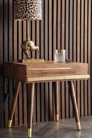 Wooden bedside table with gold lamp on top