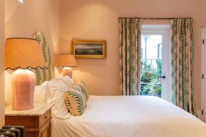 Bedroom painted in Farrow and Balls Setting plaster with green patterned curtains and headboard