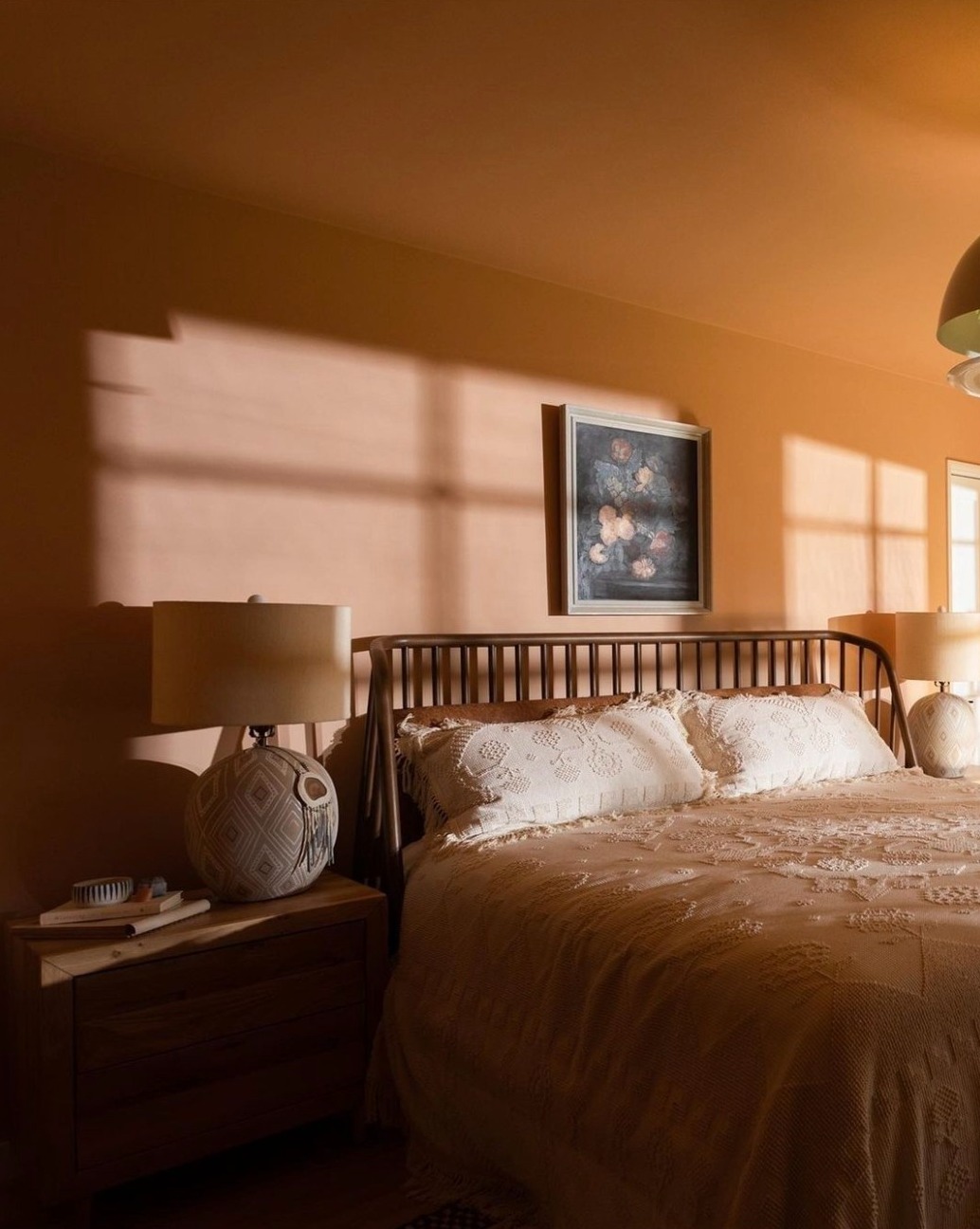 Sun shining on terracotta a bedroom wall that is painted in a warm terracotta paint colour