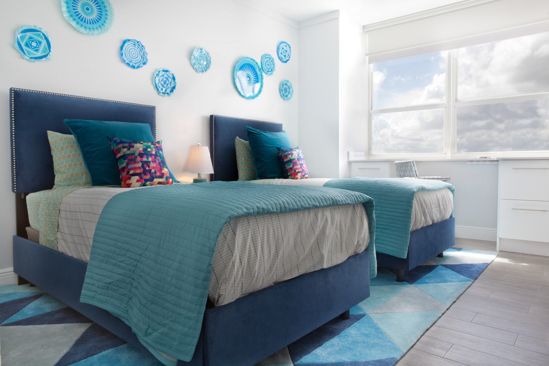 A holiday home bedroom with twin beds and blue plates on the wall as decor