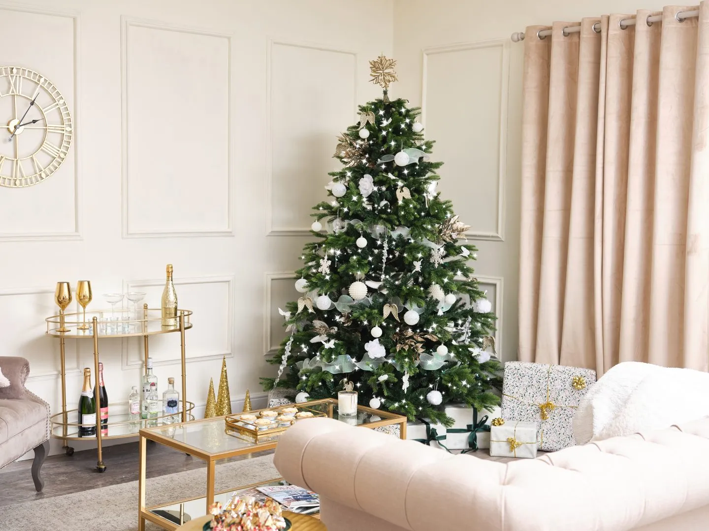 Sophisticated white and gold Christmas decorations in a large living room with high ceilings and panelled walls