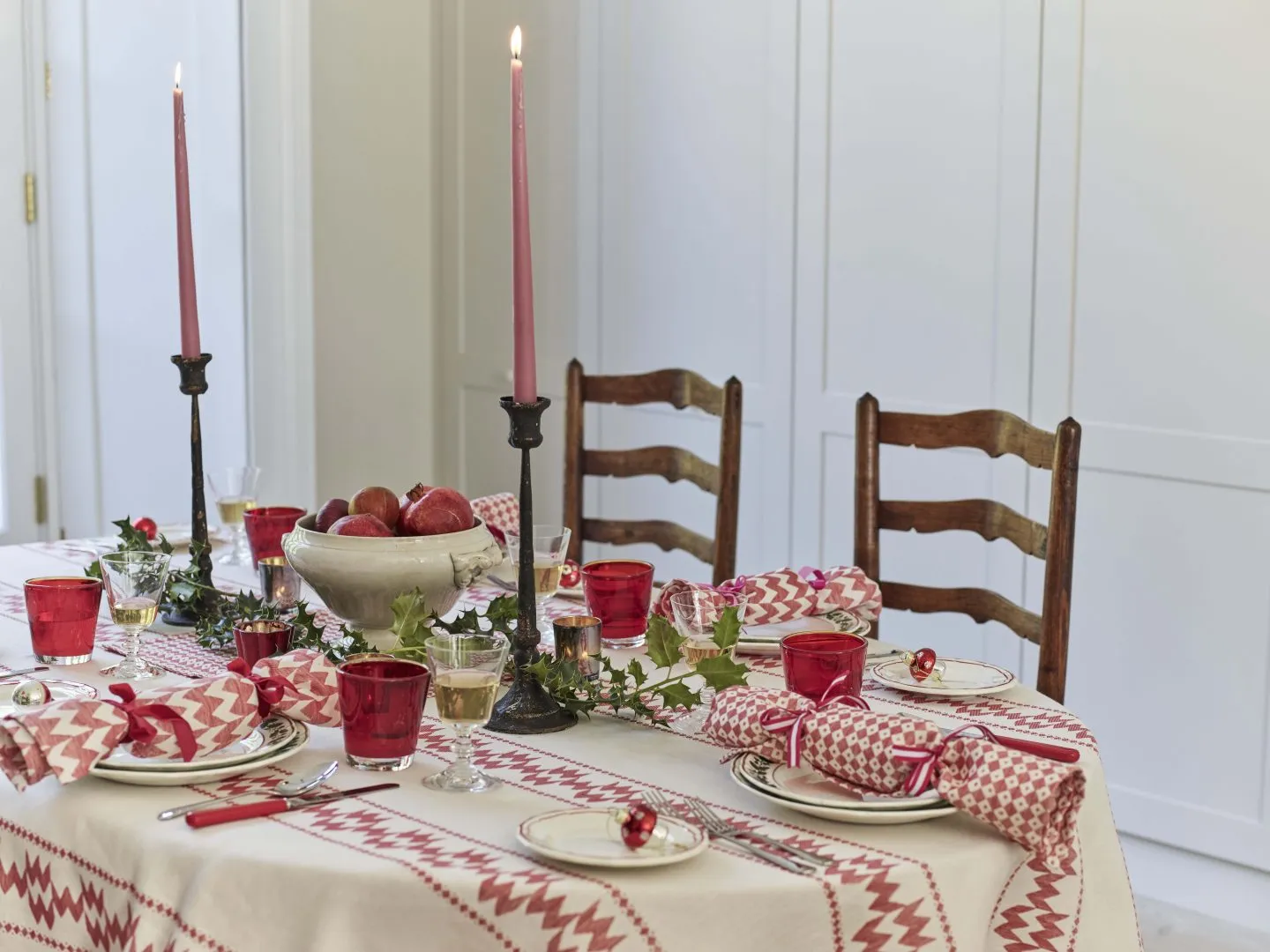 Christmas table decorated in red and white with patterned tablecloth and fabric christmas crackers