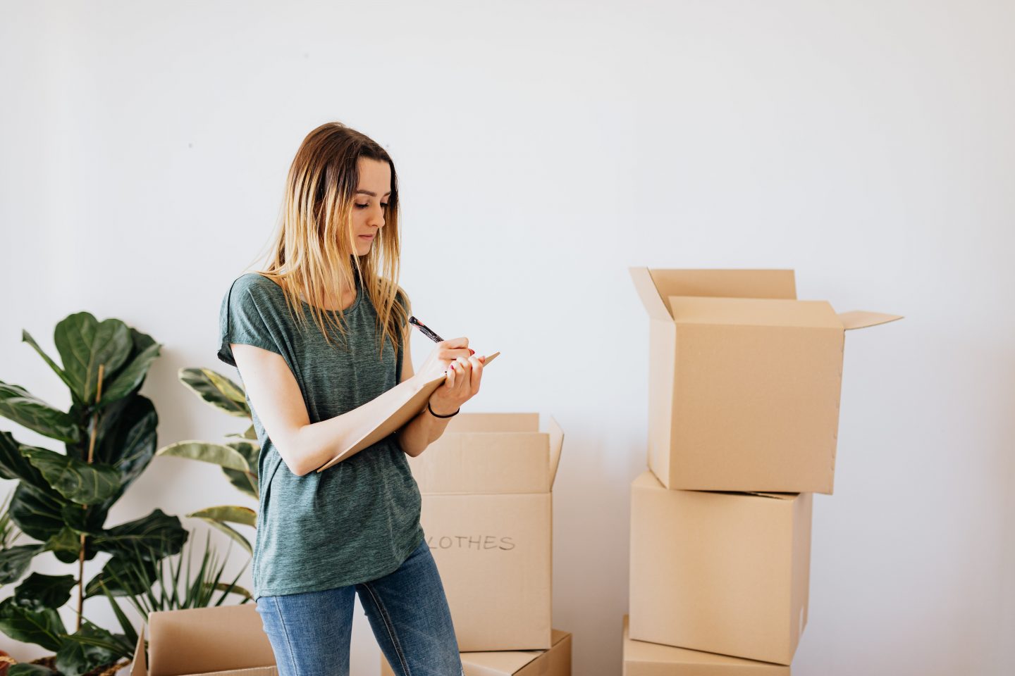 Image of a woman completing a moving house checklist and packing boxes