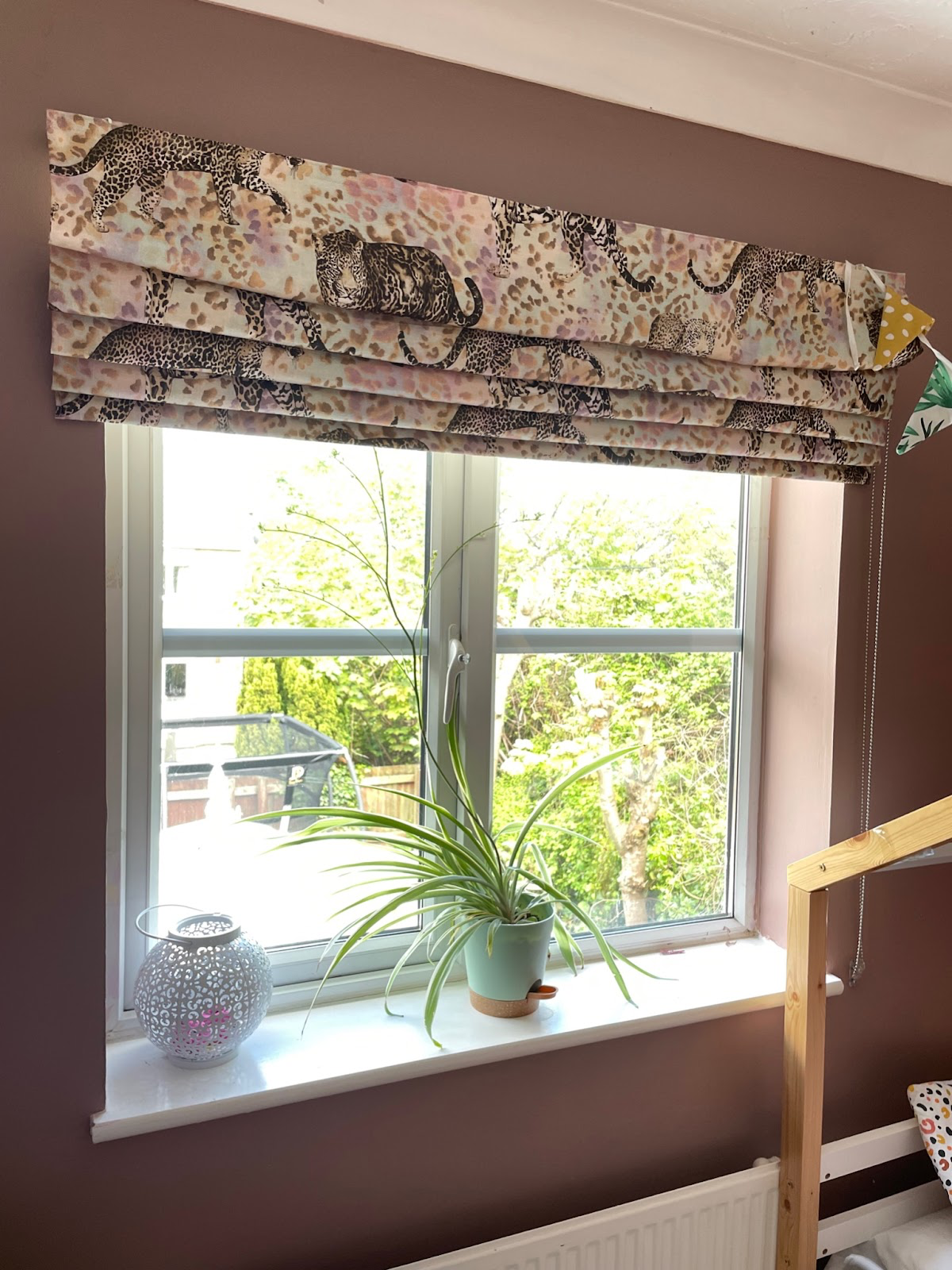 A pink and beige roman blinds with a leopard design on a leopard print background.