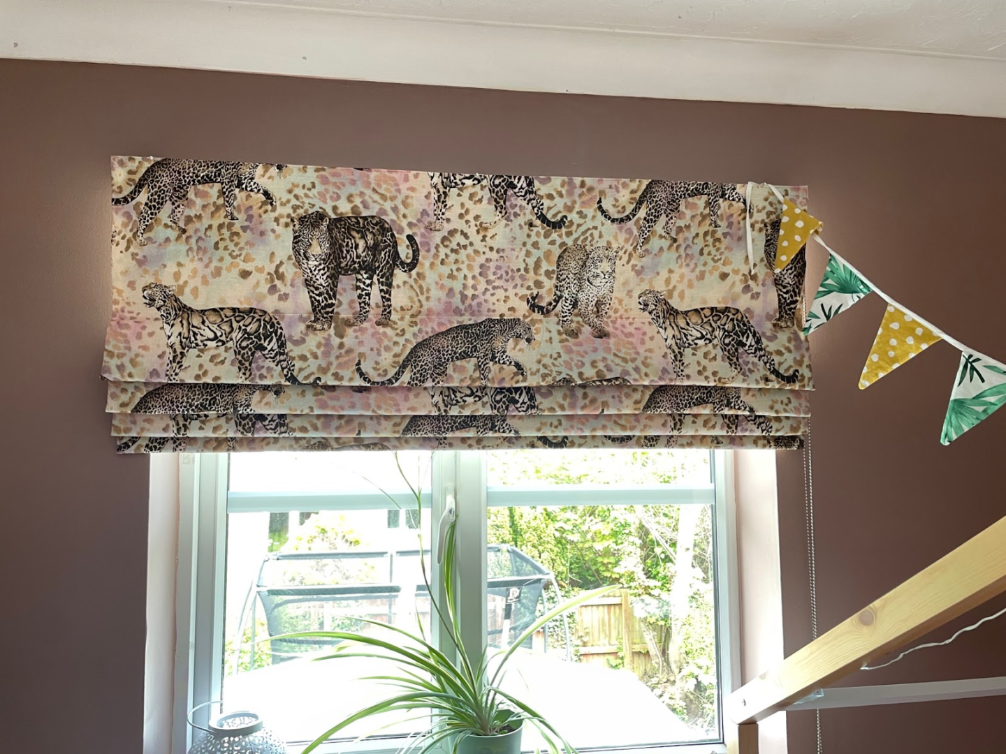 Leopard print roman blinds on a window in a bedroom painted in Farrow and Ball's sulking room pink