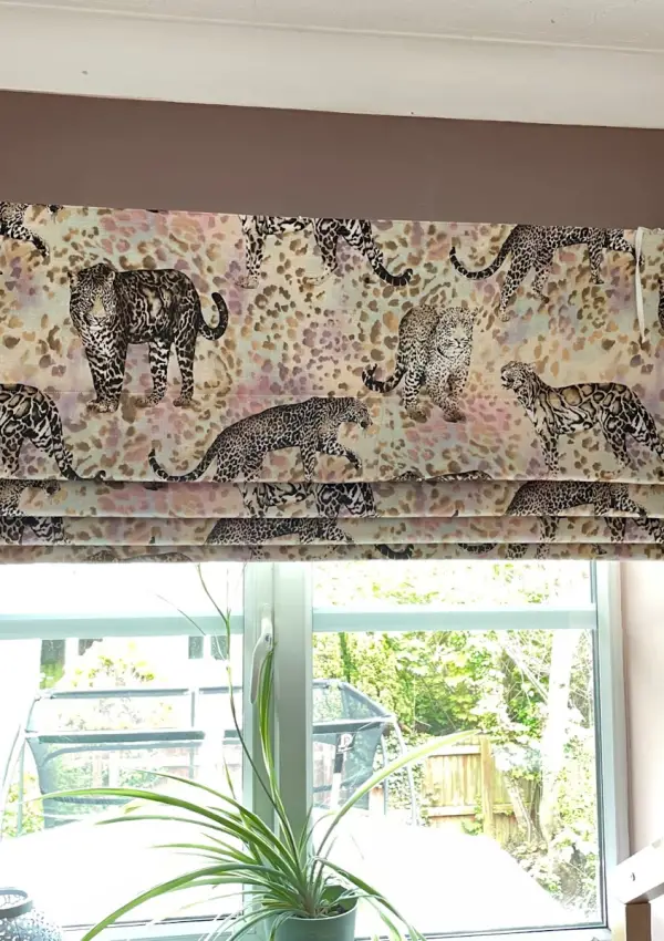 Leopard print roman blinds on a window in a bedroom painted in Farrow and Ball's sulking room pink