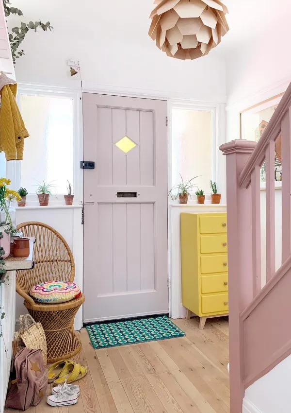 Colourful entryway with the front door painted in Peignoir by Farrow and Ball