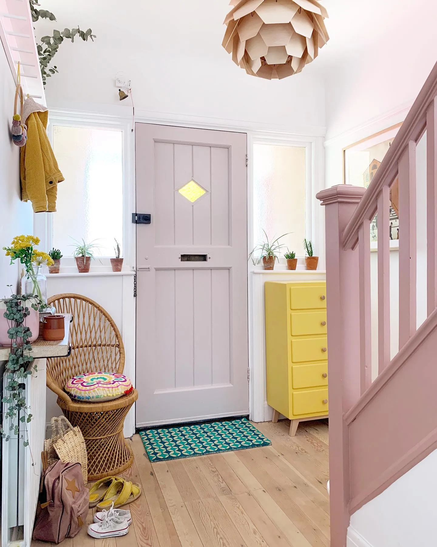 Colourful entryway with the front door painted in Peignoir by Farrow and Ball
