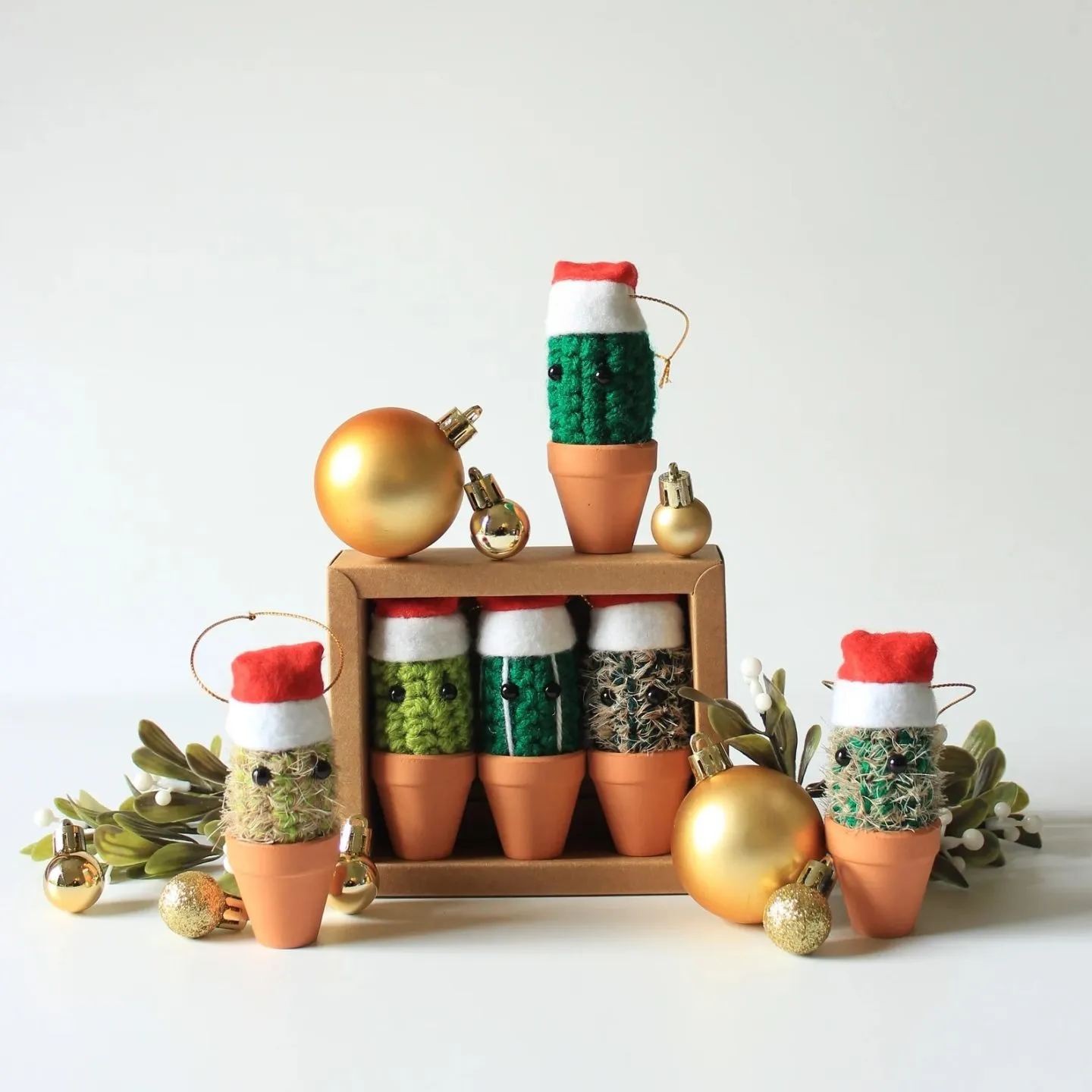 Christmas hanging decorations: Little crocheted cactuses with santa hats and a hanging loop.