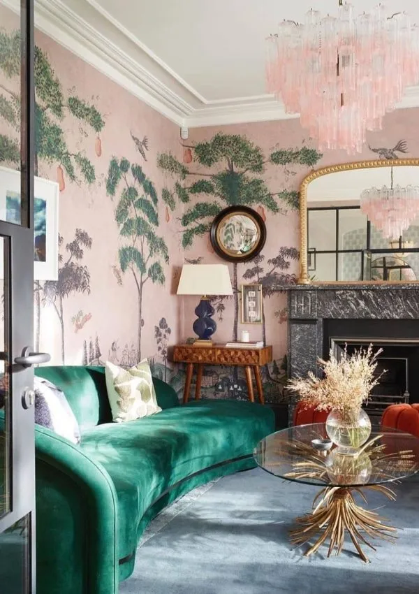An elegant living room with a pink and green chinoiserie wall mural and a green velvet sofa.