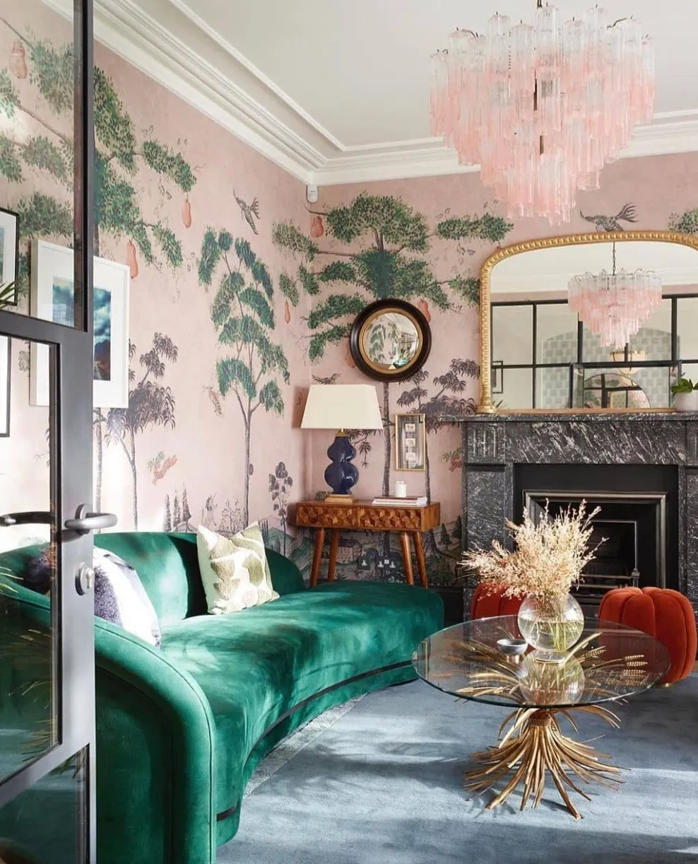An elegant living room with a pink and green chinoiserie wall mural and a green velvet sofa.