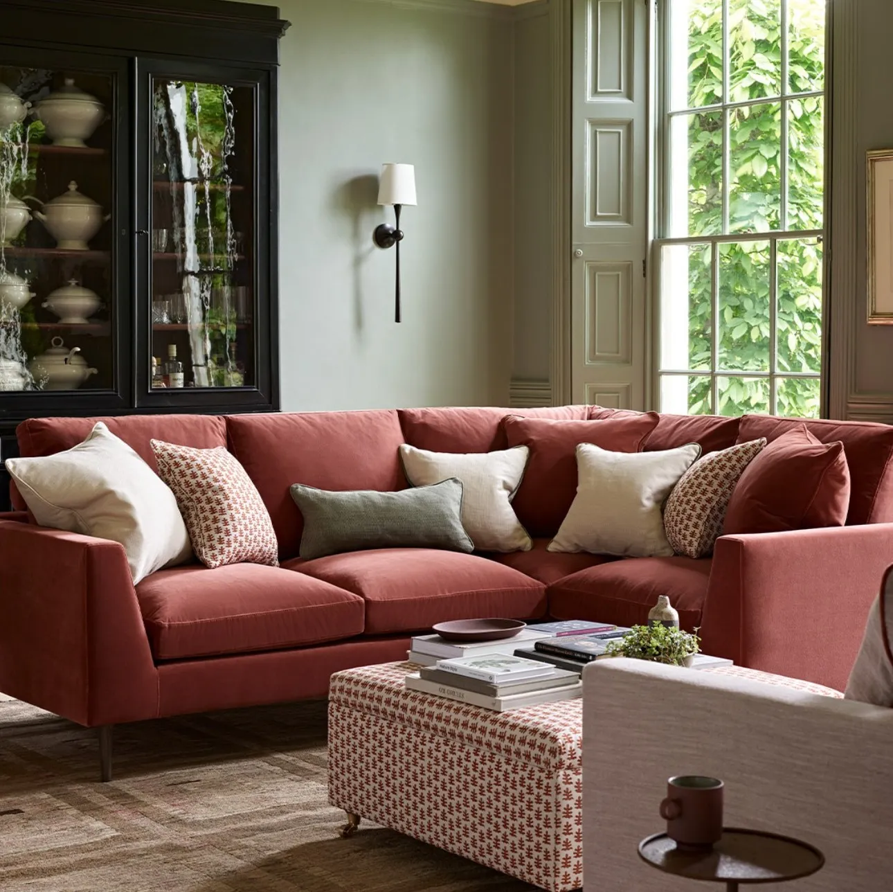 A sophisticated living room in a period home with sage green walls, one rust pink sofa and one pale pink sofa.